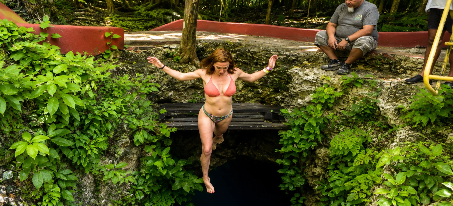 Traveler jumping into a jungle cenote during a Cancun adventure excursion