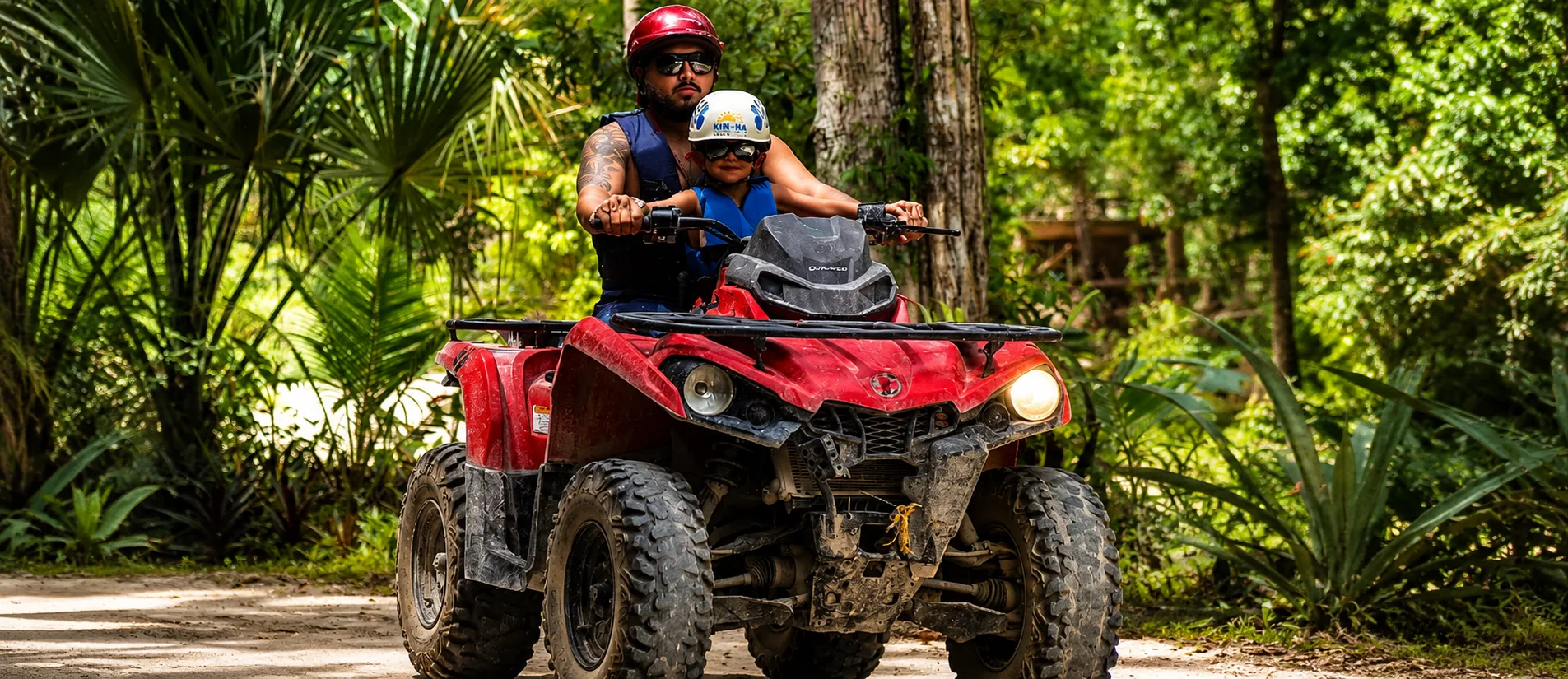 Family riding an ATV through a tropical jungle in Cancun Mexico