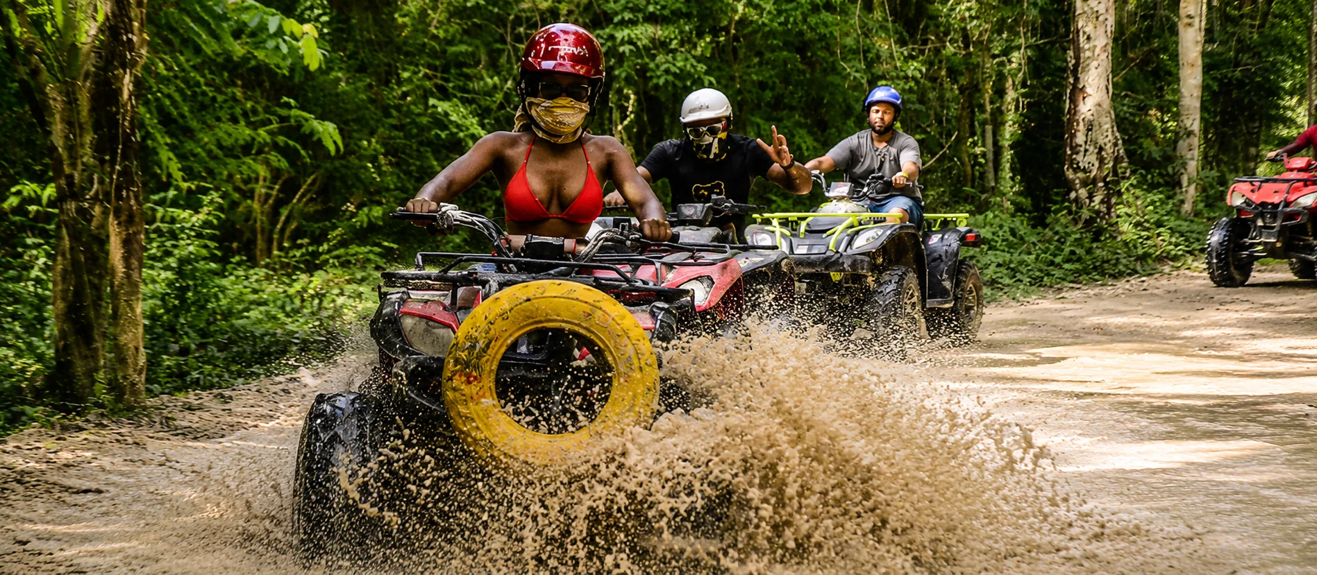 Travelers riding ATVs through muddy jungle trails during a Cancun adventure tour